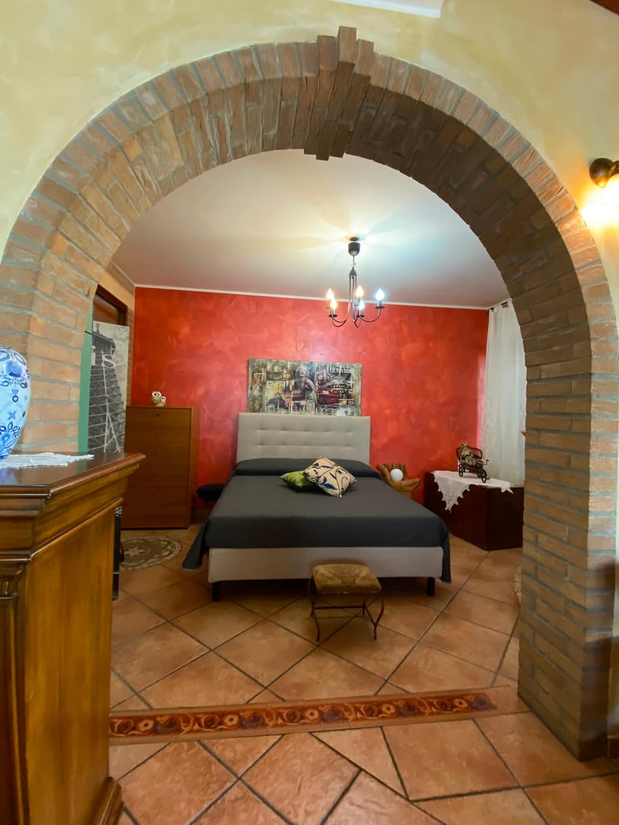 La camera matrimoniale dalla parete rossa, sotto l’arco in mattoni