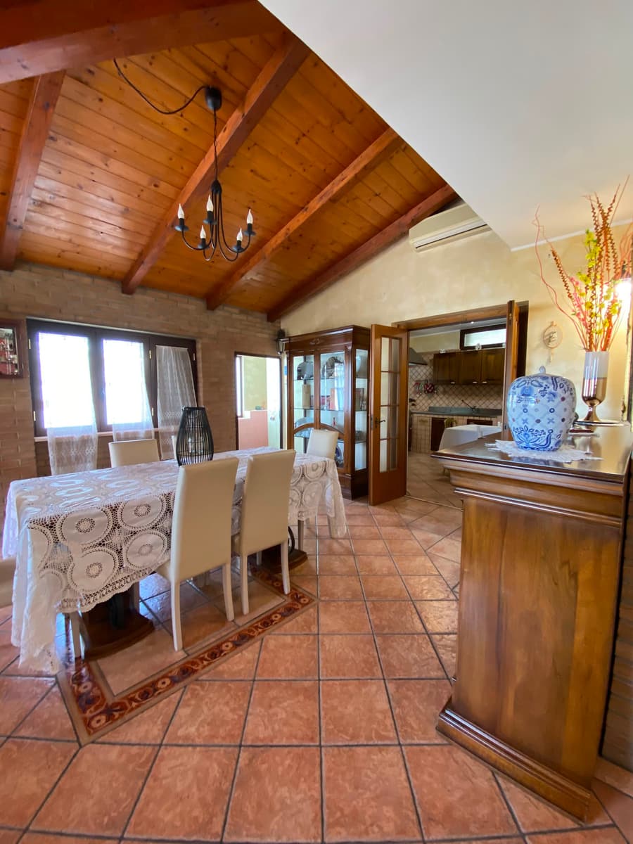 Il soggiorno con il soffitto a travi in legno a vista e il tavolo apparecchiato