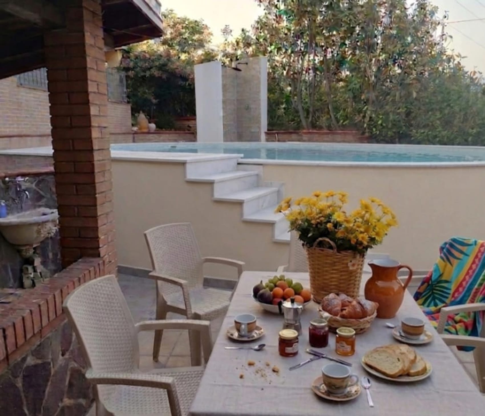 La piscina privata dello chalet vista dal terrazzo, con il tavolo apparecchiato per la colazione